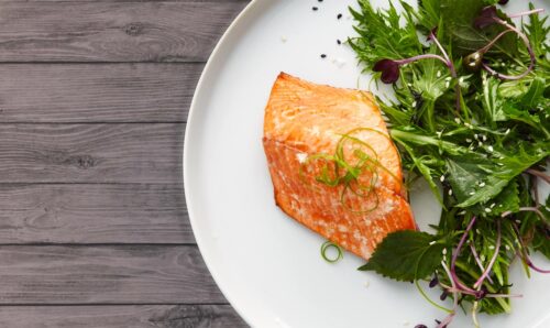 Sea to Table Brand Image - Salmon and Kale presented on white plate and wooden table